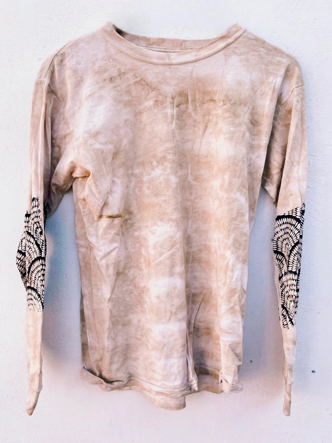 Beige tie-dye long-sleeve shirt with black patterns on sleeves against a white background